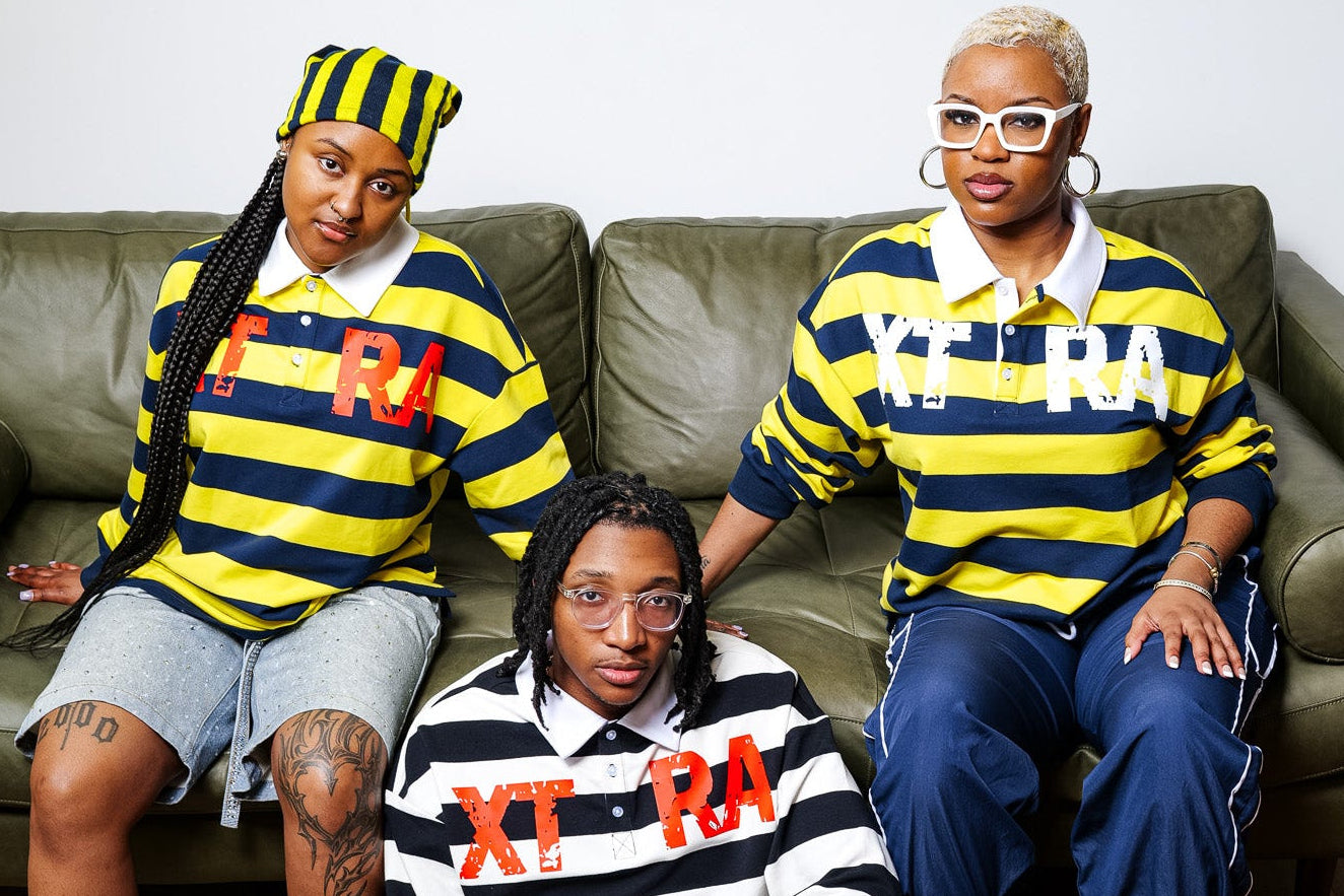 Three people sitting on a couch wearing striped shirts with visible branding.